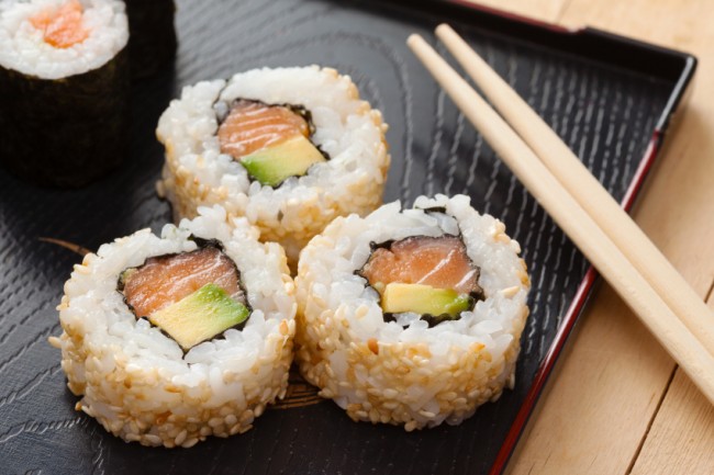 sushi rolls on black plate and chopsticks
